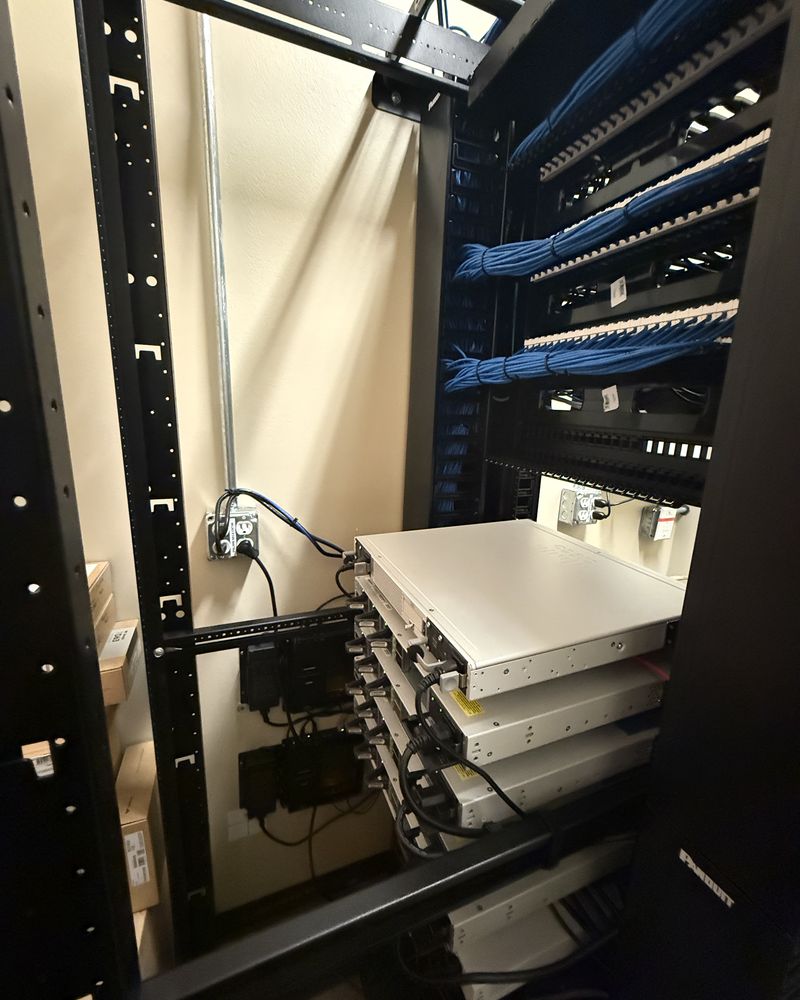 Cable bundles combed into an open-frame rack and terminated across patch panels, with switching mounted below
